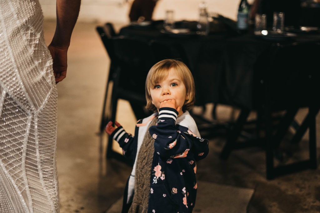 photo of a young child sucking her fingers while waiting for her parents during their anniversary party at the linen building