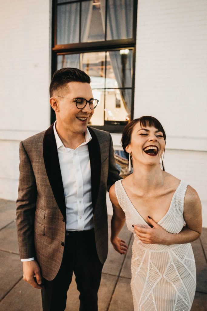 couple laughs together outside of the linen building before their anniversary party begins