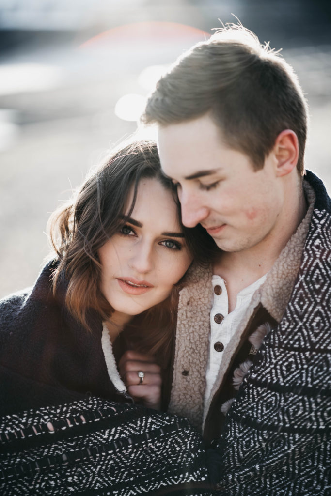 couple cuddles up together in a blanket during their snowy lucky peak lake elopement