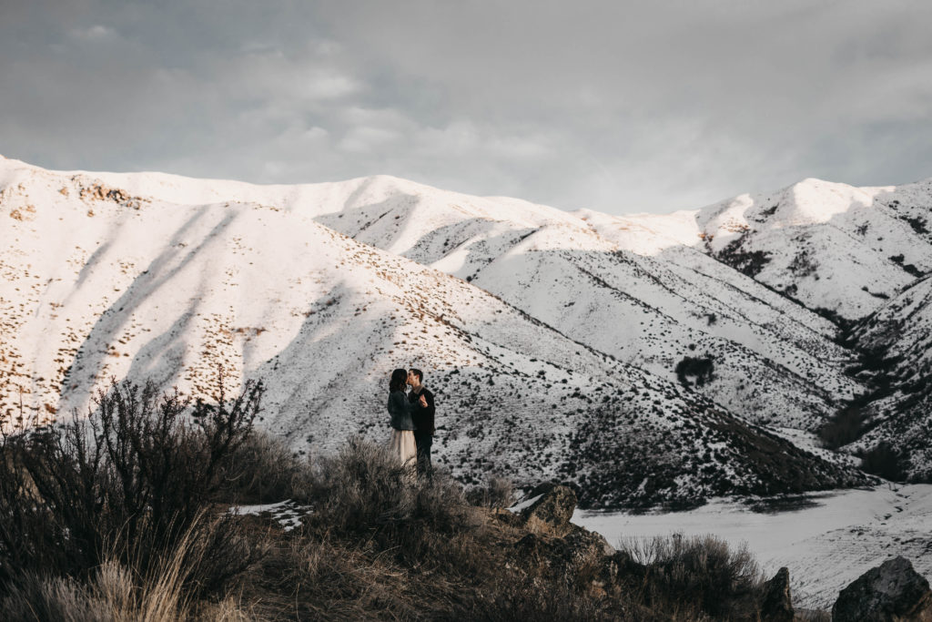 couple kisses with lucky peak lake mountains in the background during their Idaho elopement