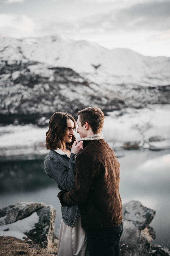 couple hugs each other as they stand in front of the lake