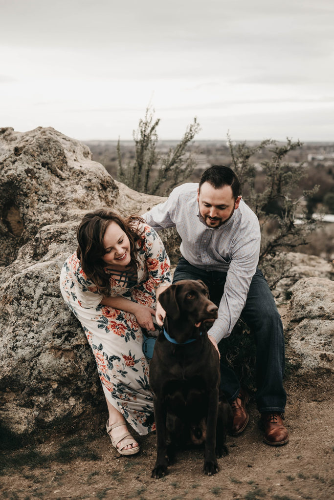 couple playing with their dog during their engagement session at military reserve
