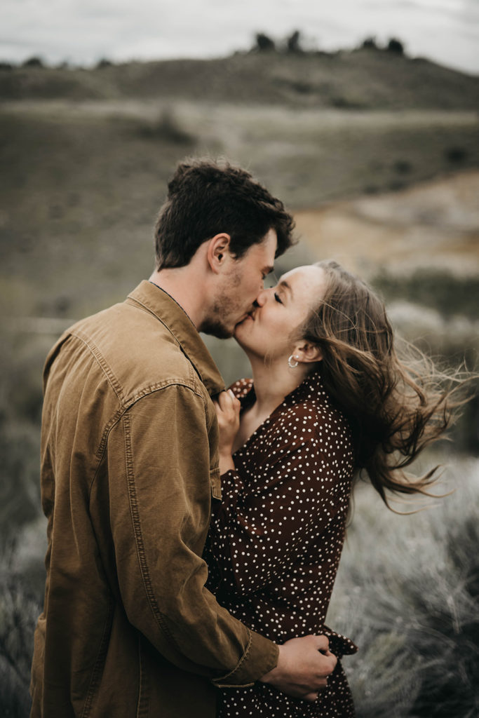 couple kisses as the wind blows during the boise foothills engagement session