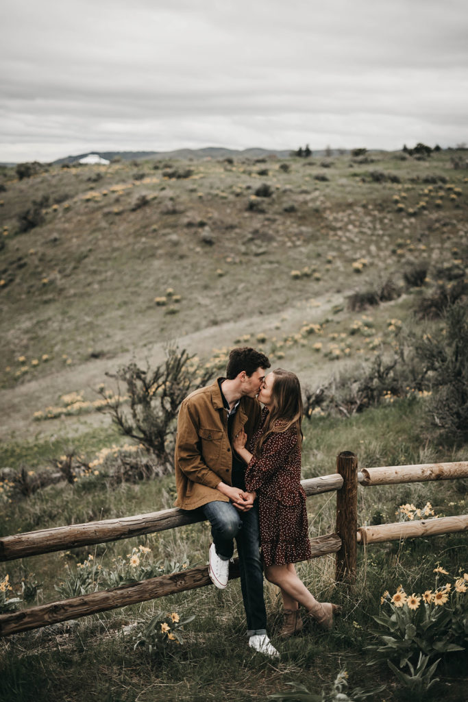 couple leans against the fencing on the boise foothills trails during their engagement session