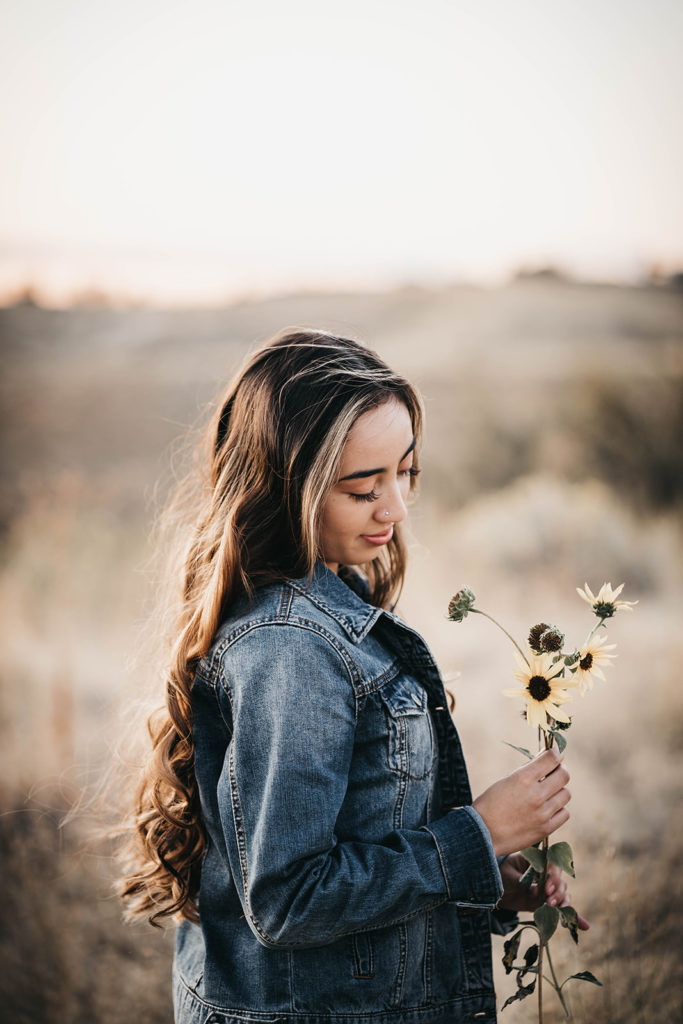 senior holds a bouquet of balsam root sunflowers in the boise foothills