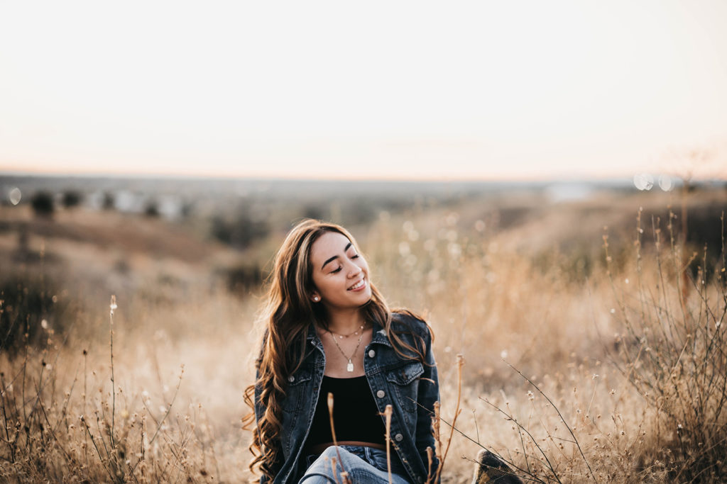 Rocky Mountain High School senior lays in the field during her senior session in the boise foothills