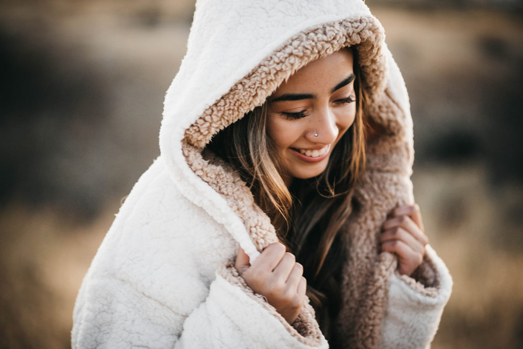 senior cuddles up in a sherpa jacket during her senior session in boise