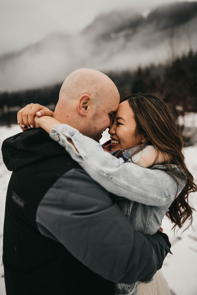 couple cuddles up together for their snowy snoqualmie pass engagement session