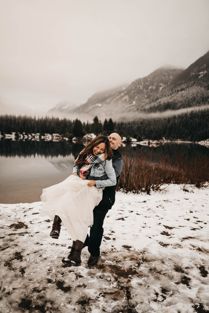 couple plays in the snow at gold creek pond during their snoqualmie pass engagement session