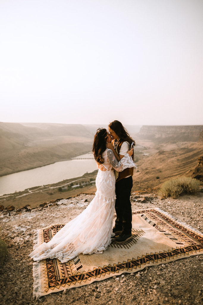 couple shares their first kiss on a persian rug overlooking the snake river canyon