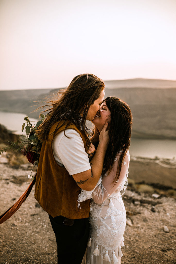 Brides leaning in to kiss each other after their elopement