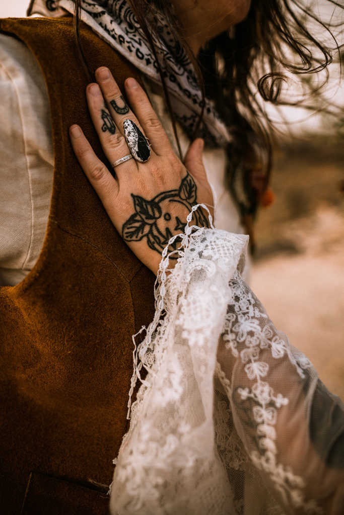 close up detail shot of bride's rings and hand tattoos