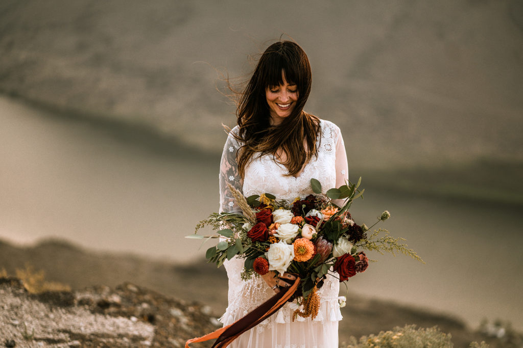 Bride looking down at her boho elopement bouquet