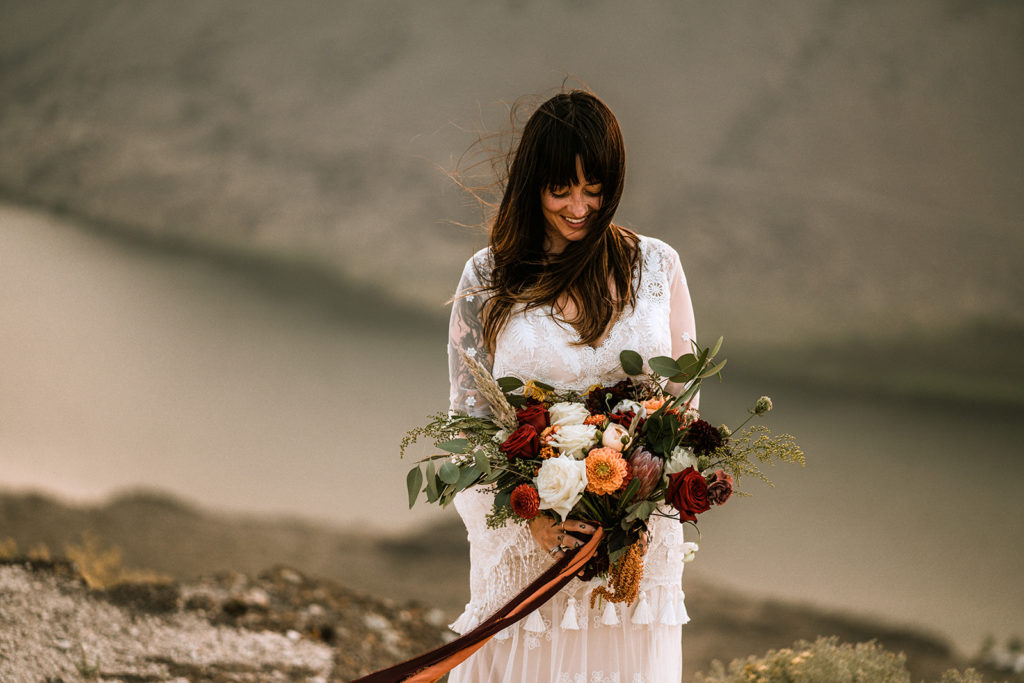 Bride holds and looks down at her elopement bridal bouquet