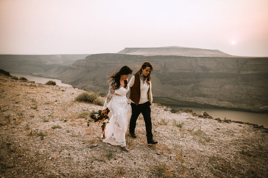 Brides walk together along the Snake River Canyon after they eloped in Idaho