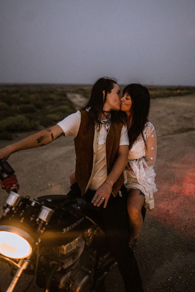 Newlywed couple kisses on a motorcycle at dusk after their elopement