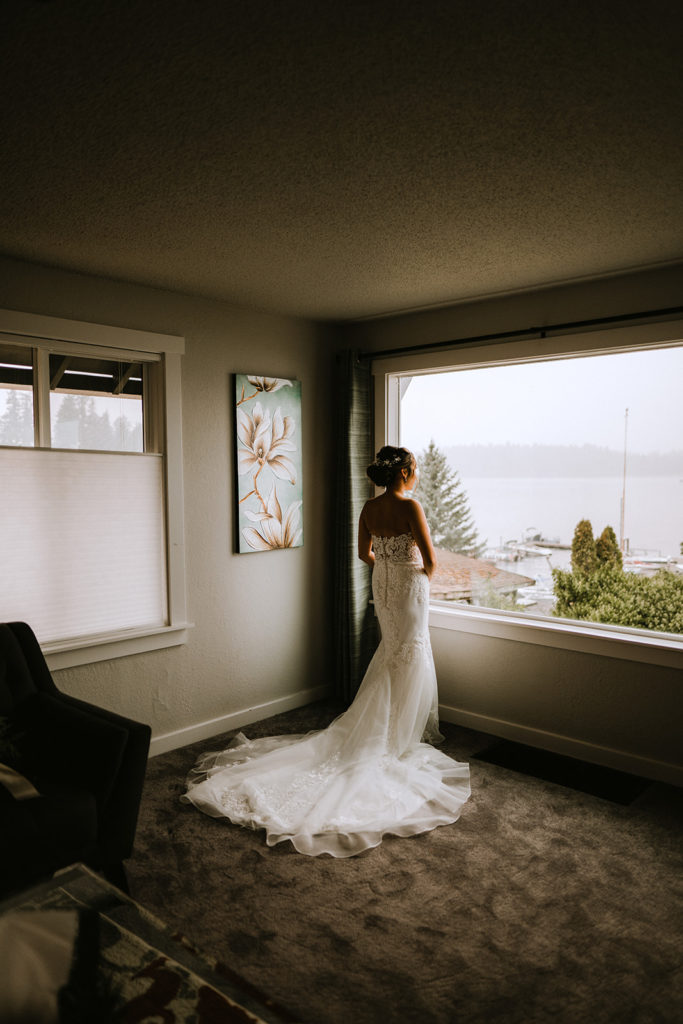 Bride waits for ceremony to begin and looks out the window to the Tacoma, Washington lake