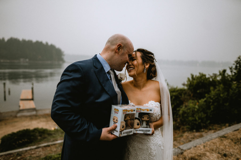Bride and groom lean in to touch foreheads together while holding their custom made personal funko pops