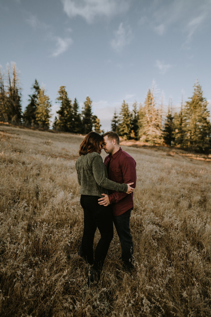 Couple holding each other in a mountain field