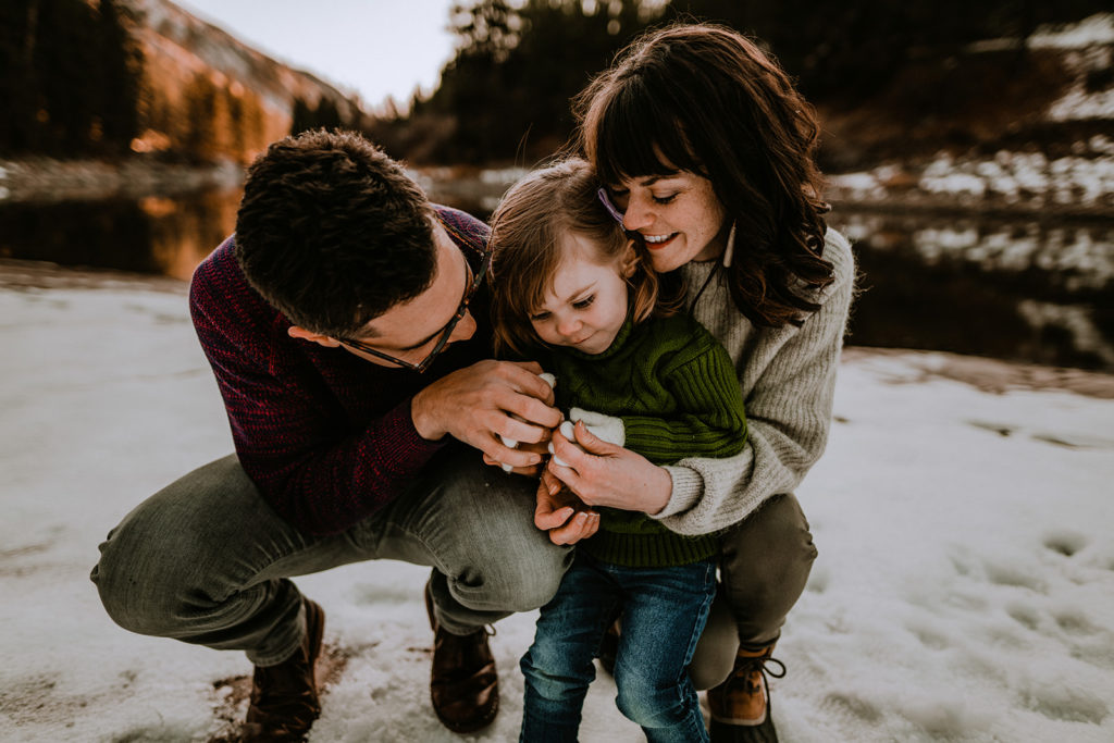 family hugs each other with gorgeous winter river background