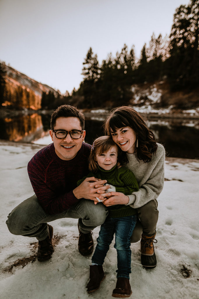 family smiles at the camera together with the Payette River and the sun set behind them