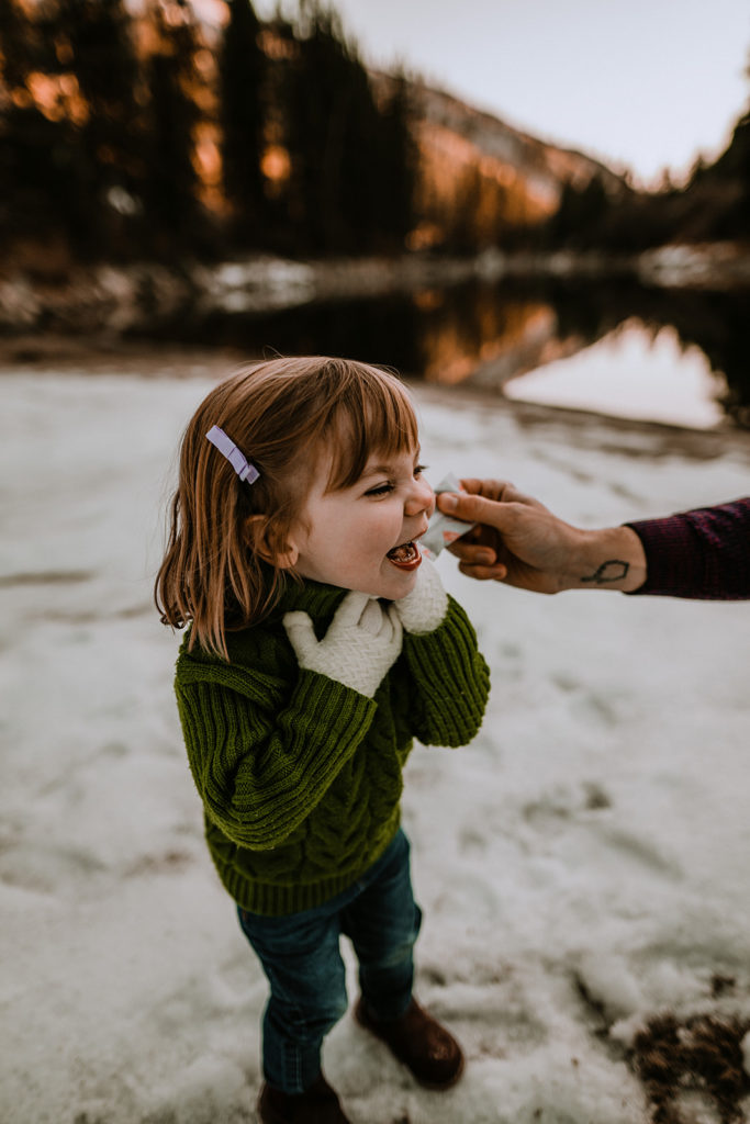 girl laughs as her father puts a hand warmer to her cheek