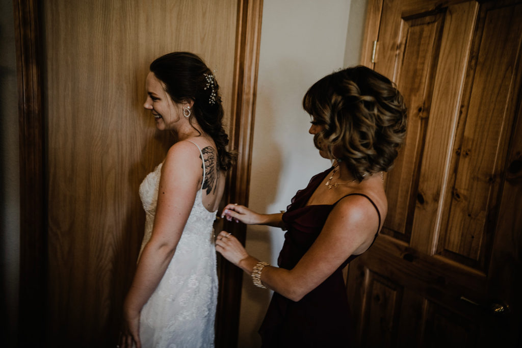 maid of honor zips up bride's dress before her intimate donnelly wedding ceremony begins