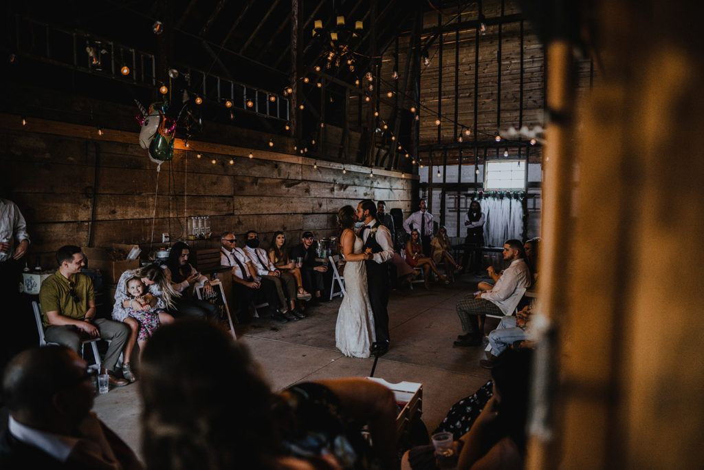 Bride and groom share their first dance in a barn as their guest look on during their intimate donnelly wedding