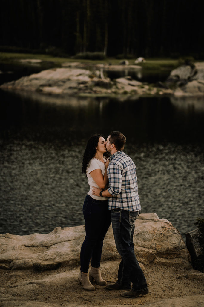 couple kissing in front of Blue Lake for their engagement session in Cascade, Idaho