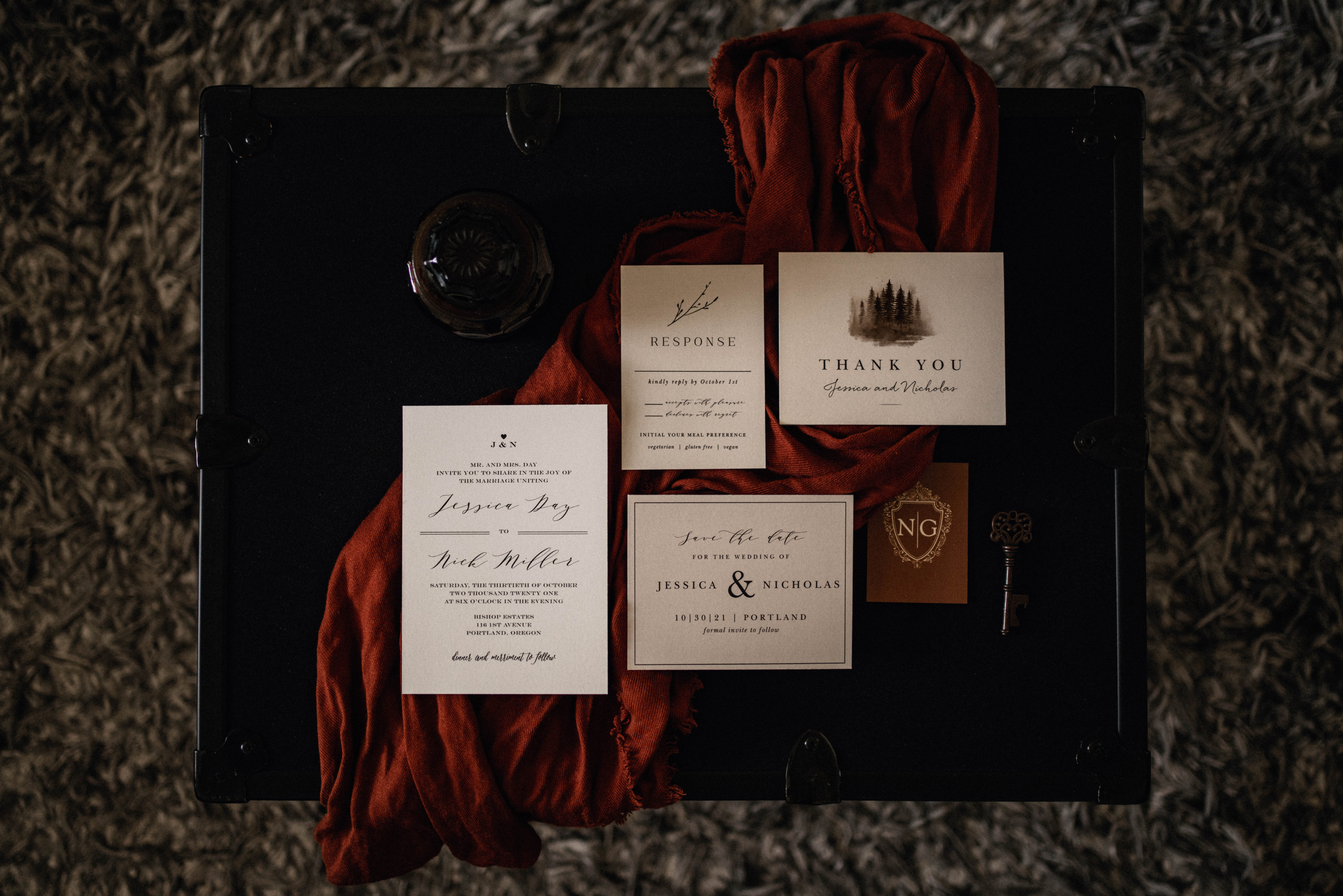 Basic Invite Wedding invitation flatlay on a black pottery barn trunk