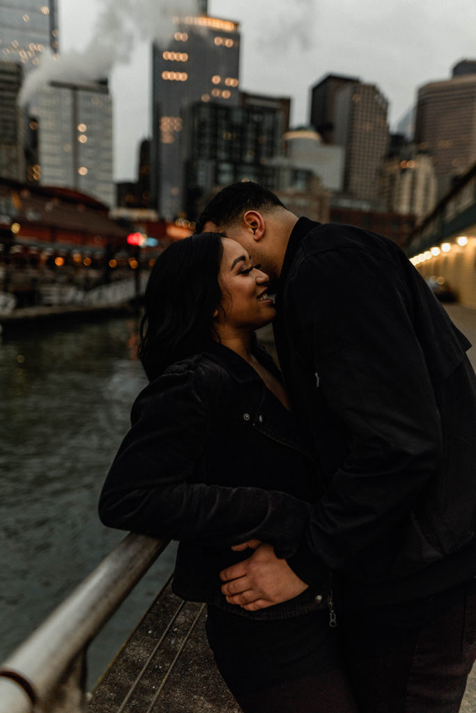 couple hanging out on the pier with downtown seattle in the background during their engagement shoot
