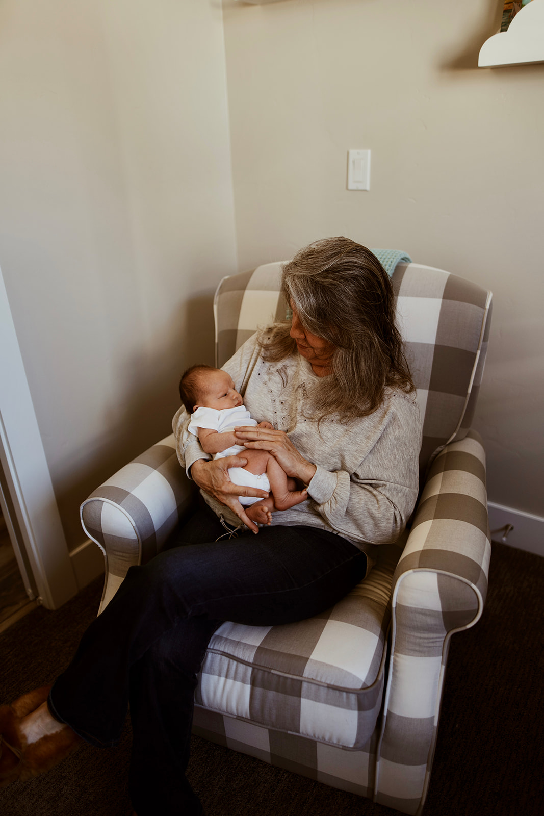 Grandmother holding her new grandson while sitting in a rocking chair during a newborn lifestyle session
