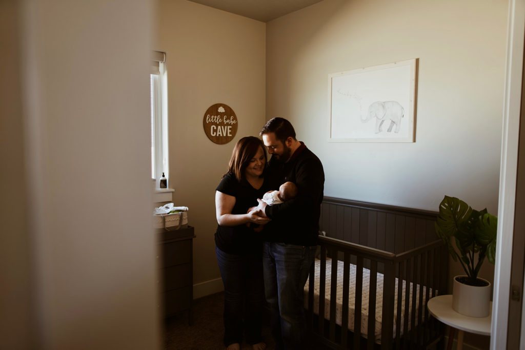 New mother and father holding their newborn baby in his nursery during their Boise Lifestyle newborn session