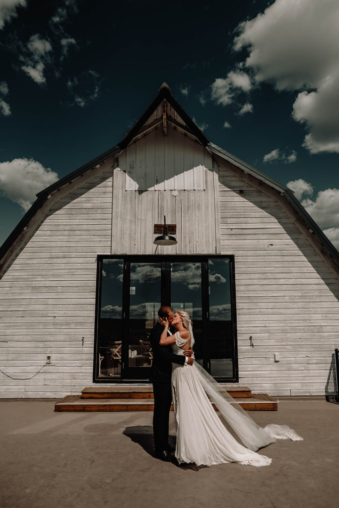 Bride and Groom share a kiss in front of the Foster Creek Farm barn after their private vow reading