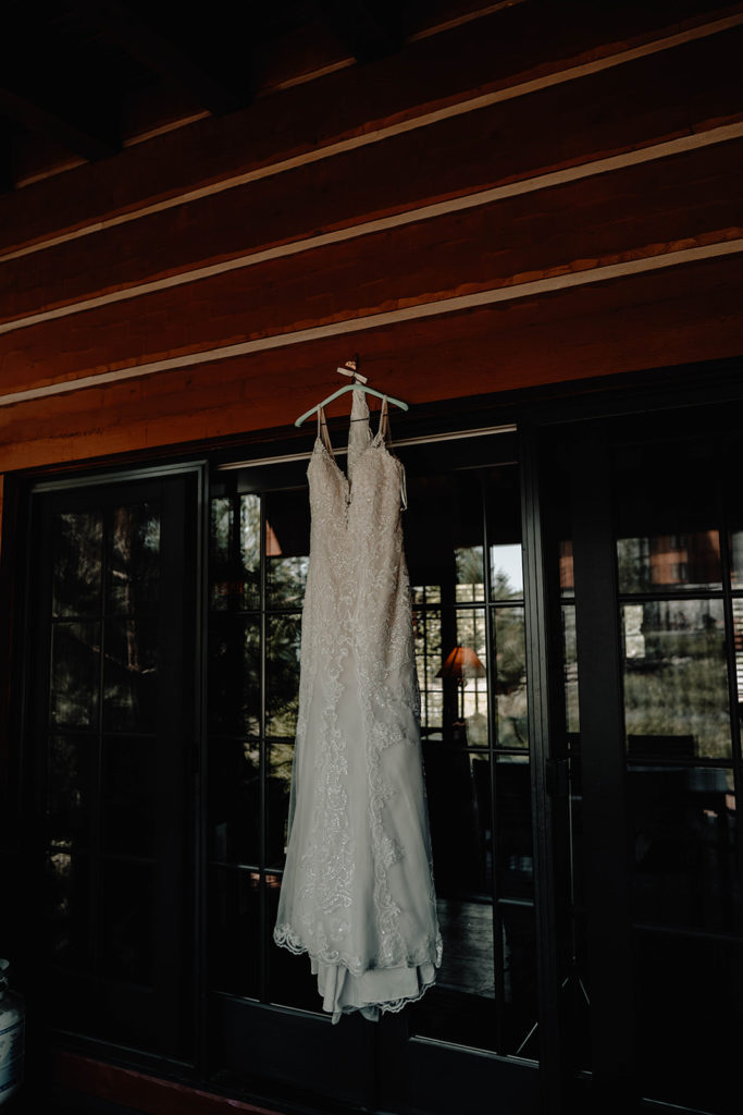 Full length photograph of BB Bridal gown hanging from a beam on the wedding cabin's patio