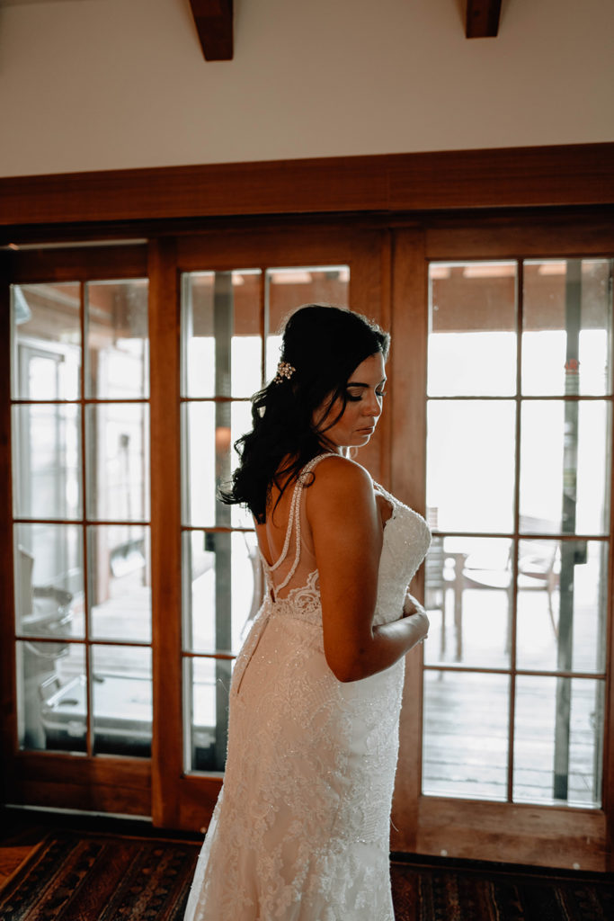 Bride stands in front of her cabin porch doors after she is finished getting ready