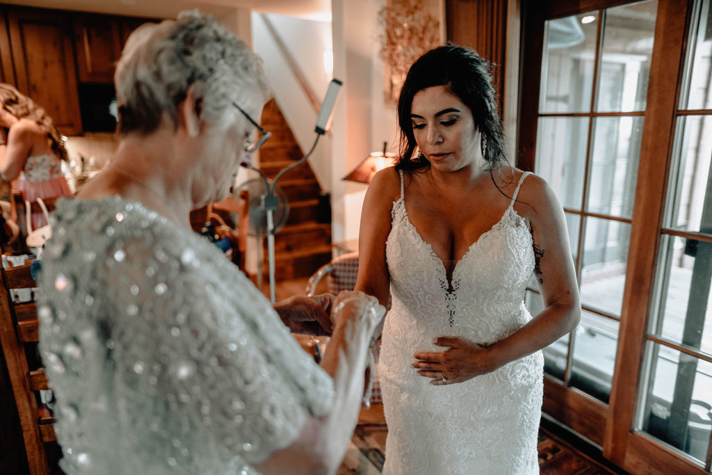 Mother of the bride helps bride with her jewelry as she gets ready for her Tamarack Resort wedding ceremony