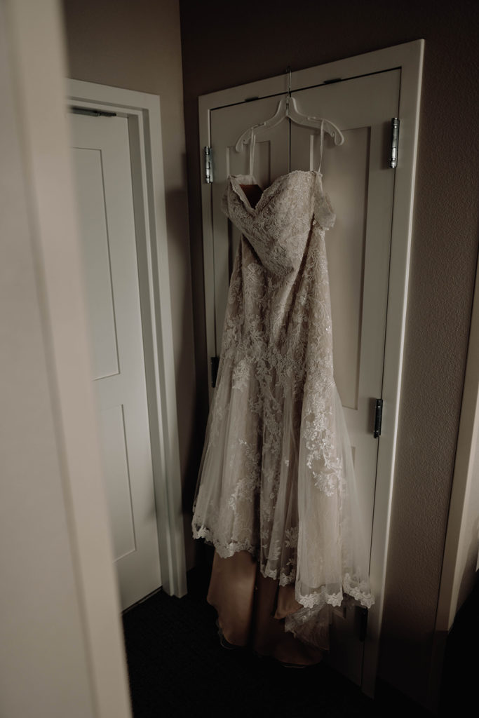 Bride's David's Bridal dress hangs on a hook over the hotel room door as she gets ready for the day