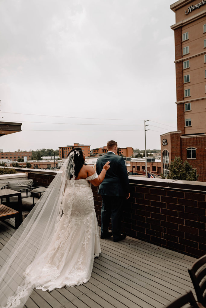 Bride taps on the groom's shoulder as he waits over looking downtown Boise for their first look
