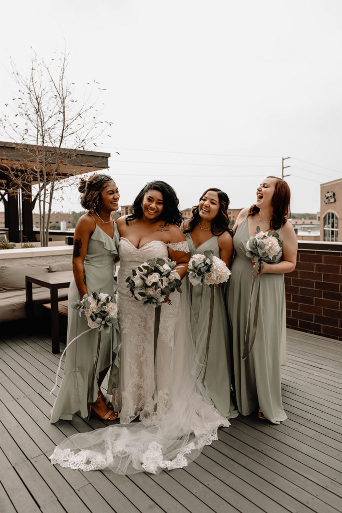 Bride and her bridal party laugh together as they take portraits with the city of Boise in the background