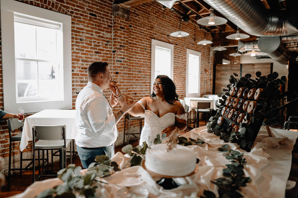 Bride and groom feed each other Pastry Perfection donuts during their wedding at Beside Bardenay