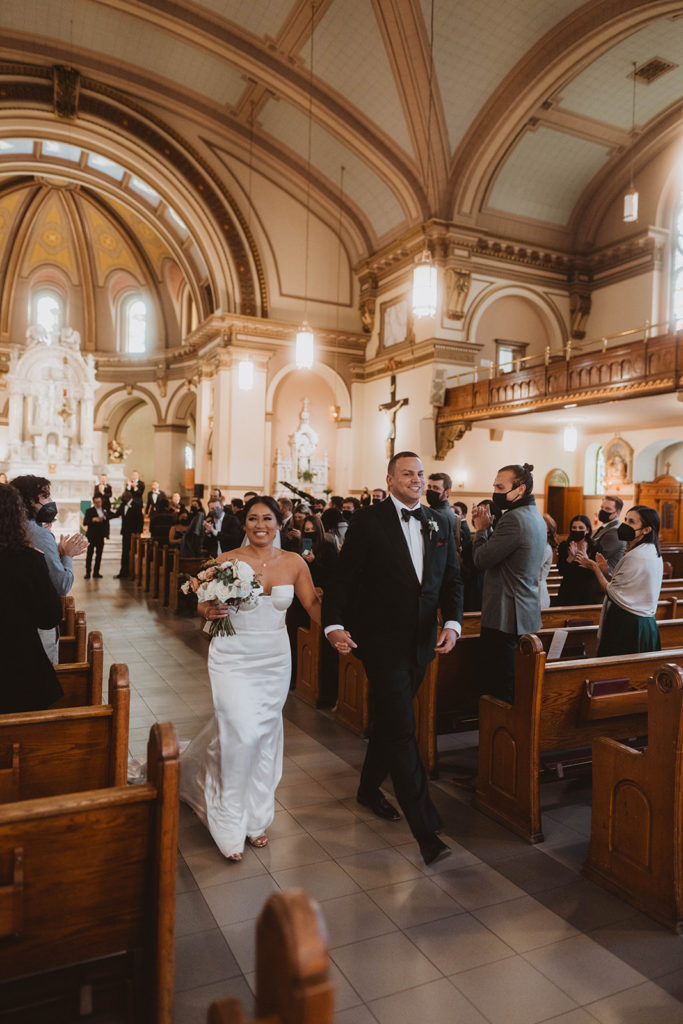 Bride and groom walk back down the aisle as newlyweds in St. Aloysius Church