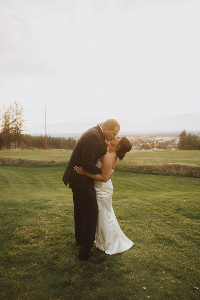 Sunset photos during the wedding at Beacon Hill Event Center overlooking Spokane. The bride and groom kiss in the dreamy sunlight.
