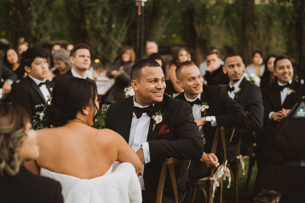 Groom looks on an smiles as his Best Man gives his speech