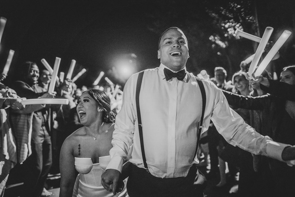 Bride and groom celebrate while walking through their glowing wand exit at the end of the wedding day