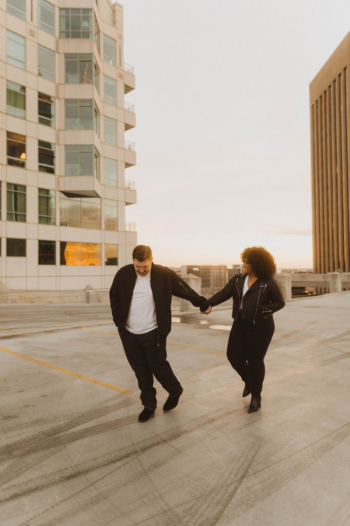 couple holds hands and walks along the parking garage