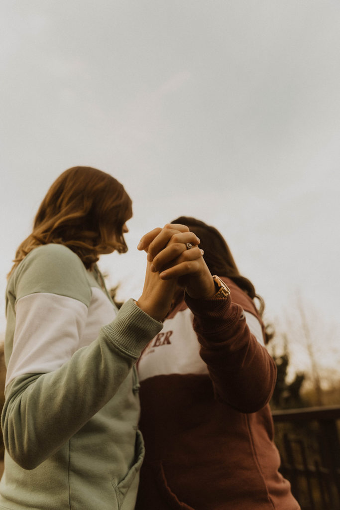couples hands in focus as they dance together under an overcast fall sky