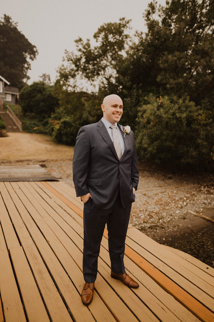groom stands on the dock at American Lake in Tacoma waiting for the bride for the first look