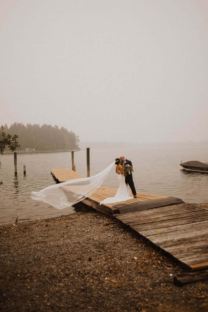 bride and groom kiss on the dock on American lake during the first look for their lakeside Tacoma elopement