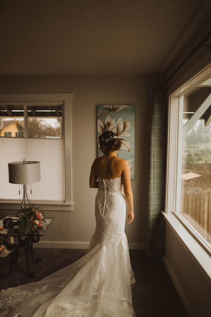 bride looks back at her wedding bouquet in front of a large window at the airbnb for her tacoma elopement